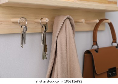 Wooden hanger for keys on light grey wall, closeup