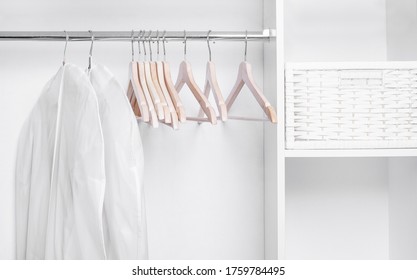 Wooden Hangers And Covers For Clothes In A White Minimalistic Wardrobe. Hanging Garment Bag.