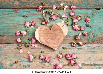 Wooden heart with dried rose flowers on the turquoise old wooden background with copy space. Flowers composition. Flat lay, top view