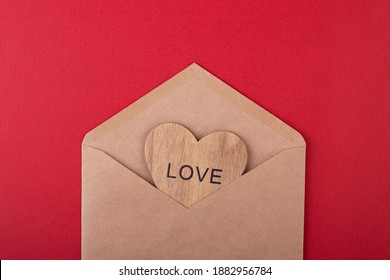 wooden heart with the inscription love in a craft envelope on a red background. Valentine's day. mother's day - Powered by Shutterstock