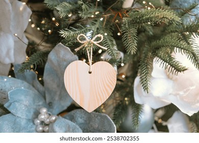 A wooden heart ornament is gracefully hung on a Christmas tree adorned with soft blue flowers and twinkling lights, creating a cozy holiday atmosphere. - Powered by Shutterstock