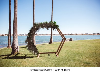 Wooden Hexagon Wedding Arch With Tropical Leaves Decor. Honeycomb Wedding Arch With Monstera And Palm Trees Leaves.