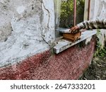 A wooden hive used for keeping stingless bees (tribe Meliponini, family Apidae) placed on a concrete window ledge, with a beekeeper s hand adjusting the lid. 