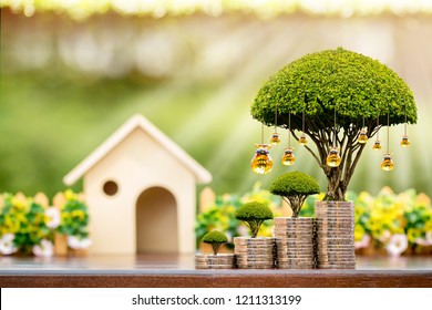 Wooden home and stacked coin and a golden money bag of tree with grow value on sunlight in the public park, Saving or investment for buy a real estate and house concept.