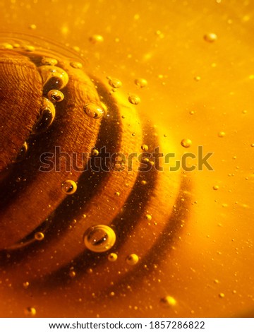 Wooden honey dipper with golden honey and air bubbles. Extreme close up