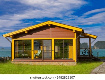 Wooden house. Country commode. Villa with panoramic windows. Bicycle is standing on terrace of house. Cottage for country house. Summer eco housing. Rustic cottage with green lawn. - Powered by Shutterstock