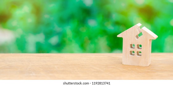 A Wooden House With A Crack. The Concept Of A Damaged House, Dilapidated Housing. Renovation, Repair And Restoration Of The Old Building. Property Insurance. Weather Element. Damage.