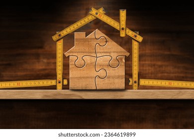 Wooden house made from a folding ruler and jigsaw  puzzle pieces, on a wooden workbench with copy space. Construction industry and interior design concept. - Shutterstock ID 2364619899