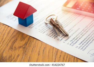 Wooden house miniature and house key lying on contract