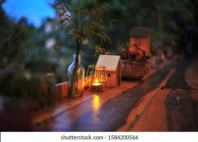 Wooden House Model ,Flowers And Candle Decorate On The Wooden Terrace In Organic Farm Stay At Night