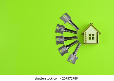 Wooden House Model And House Keys On A Colored Background. Real Estate Buying And Selling Concept. Top View, Flat Lay.