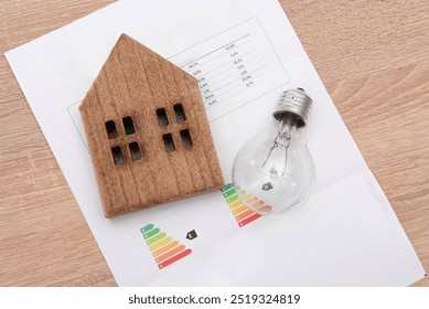 Wooden House Model and and light bulb on Energy Efficiency Rating Chart, electricity prices and tax payments concept - Powered by Shutterstock