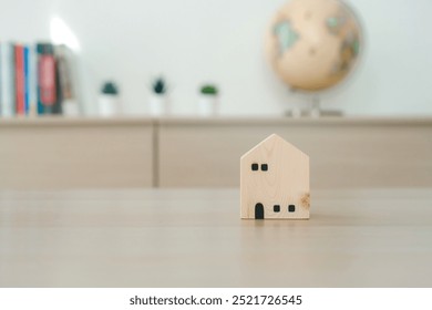 Wooden House Model on Desk with Globe in Background. Real Estate, Global Property Investment, and Homeownership. Concept of Future Planning, International Business, and Housing Development - Powered by Shutterstock