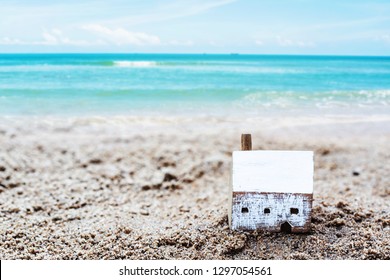 Wooden house model on the rock with blurred seascape background, Christian concept foolish man built house on the sand