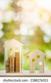 Wooden house model put on the bottle with gold coin inside of sunlight in the public park, Saving money or loan for business investment real estate or buy a new home for a family concept. - Shutterstock ID 2188276315
