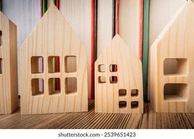 Wooden house models next to stacked books in a cozy study space highlighting educational concepts - Powered by Shutterstock