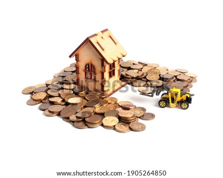 a wooden house and a pile of metal coins raked by a loader tractor