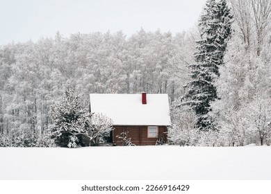 Wooden house in snow fairy forest. Winter scenery with small cottage surrounded by trees covered with snow and frost.  - Powered by Shutterstock