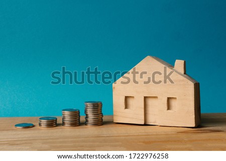 Wooden house and stacks of coins. Real estate investment for buying own home.  The accumulation of money for housing. 