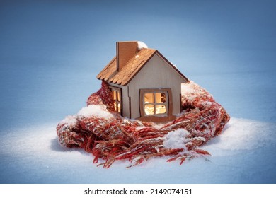 A Wooden House In The Winter In The Snow Stands On A Warm Knitted Scarf, Smart Home, The Concept Of Insulation And Heating Of Housing In The Cold, Eco-house