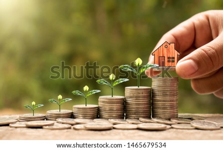 Wooden houses on coins, stack with financial growth, save money to buy houses and business investments for real estate concepts.