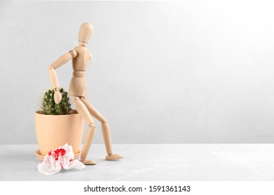 Wooden human figure, cactus and sheet of toilet paper with blood on table, space for text. Hemorrhoid problems