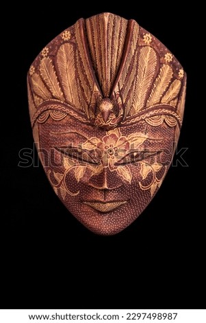 Wooden Indonesian decorative mask against a black background