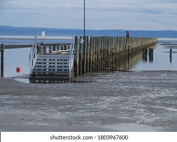wooden jetty in a sandy beach at low tide