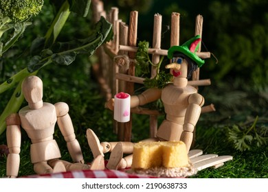 Wooden Jointed Doll Holding A Glass Of Juice And Wearing A Silly Putty Hat