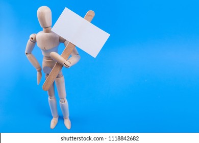 Wooden Jointed Mannequin Holding A Blank Picket Sign On A Solid Blue Background 