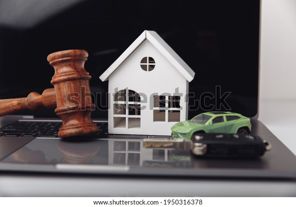 Wooden judge gavel with house and car with key.\
Auction and bidding\
concept