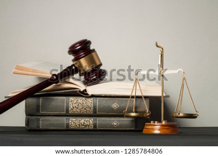 Wooden judge gavel,law scales and stack of books on table in a courtroom.Concept of justice and law.