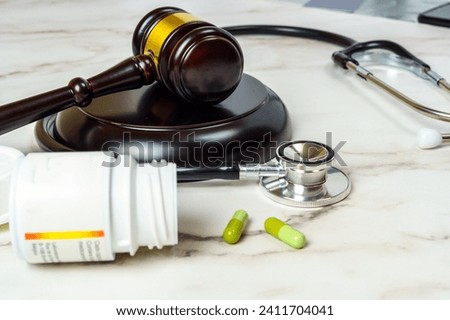 Wooden judge's hammer next to a pack of pills and a stethoscope on a table. Right to ensure access to medical care.