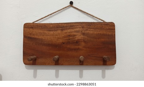 The wooden key holder in the picture is a simple yet elegant design. The hooks are arranged in a line near the bottom of the base, leaving plenty of room for other decorative elements.