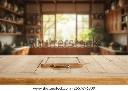 Wooden kitchen table with empty space for showcasing a product with blurred bright and cozy kitchen interior and warm sunlight streaming through a large window.