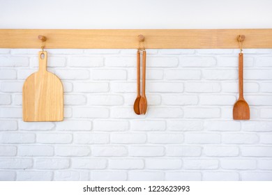 Wooden Kitchen Tools Hanging On The Bricks Wall Close Up.