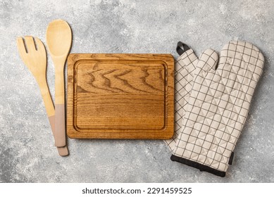 Wooden kitchen utensils, cutting board, potholder and glove on the table, top view. Kitchen Mitten and protective oven mitts on the table. Kitchenware. Kitchen accessories.Close-up.