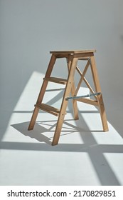 Wooden ladder in emty white room in harsh sun light with shadow. modern furniture on studio cyclorama
