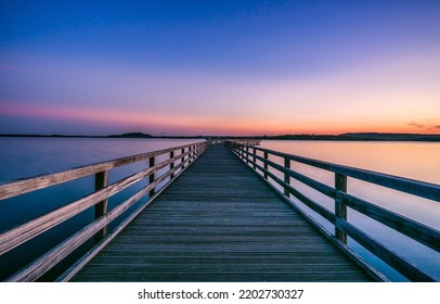 Wooden lake pier at dawn. Lake pier at dawn. Beautiful sunrise over lake pier. Lake pier at dawn landscape