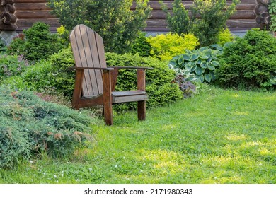 Wooden large chair among perennial ornamental plants for relaxing on a green lawn in the shade. - Shutterstock ID 2171980343