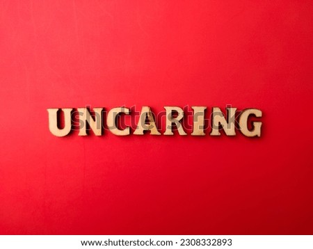 Wooden letters arranged into the word UNCARING on a red background