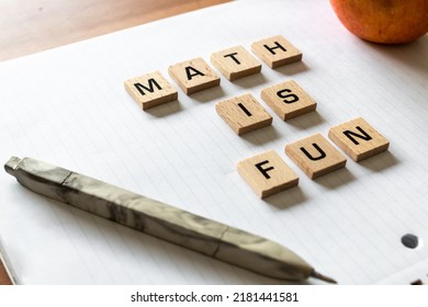 Wooden Letters Spell Out 'math Is Fun' On A Blank White Lined Notepad Beside A Red Apple And A Pen. Hardwood Desk Surface. Back To School, In-person Learning, Online Learning, Studying, No People.