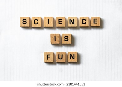 Wooden Letters Spell Out 'science Is Fun' On A Blank White Lined Notepad. Hardwood Desk Surface. Back To School, In-person Learning, Online Learning, Studying, No People, Studies, Primary School.