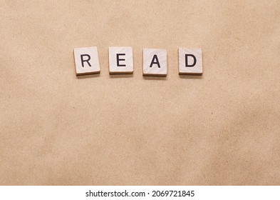 Wooden Letters Tiles Spelling The Word READ Isolated On Brown Background With Copy Space. Educational Concept For Teachers And Librarians To Add List Of Books For Students To Read.