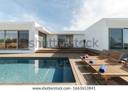 Wooden lounge chairs in modern villa pool and deck