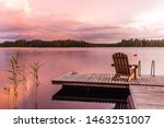 Wooden lounge chairs at Sunset on a pier on the shores of the calm Saimaa lake in Finland under a nordic sky on fire 