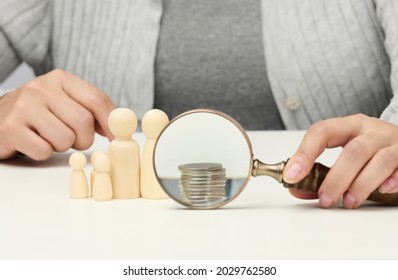 Wooden Magnifier And White Coins On The White Table. Income Growth Concept, High Percentage Of Investment. Search For New Sources Of Income, Subsidy