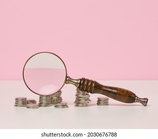 Wooden Magnifier And White Coins On The Table. Income Growth Concept, High Percentage Of Investment. Search For New Sources Of Income, Subsidy