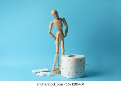 Wooden man, candles and toilet paper on blue background. Hemorrhoids