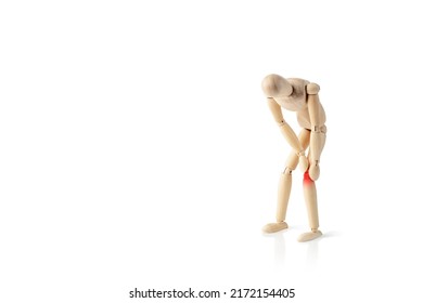 Wooden man holds his hands on sore knee isolated on white background. Concept of pain in the knee. Having knee ache. Copy space.